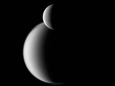 На фото видно покритий льодом супутник Рея на тлі туманного Титана